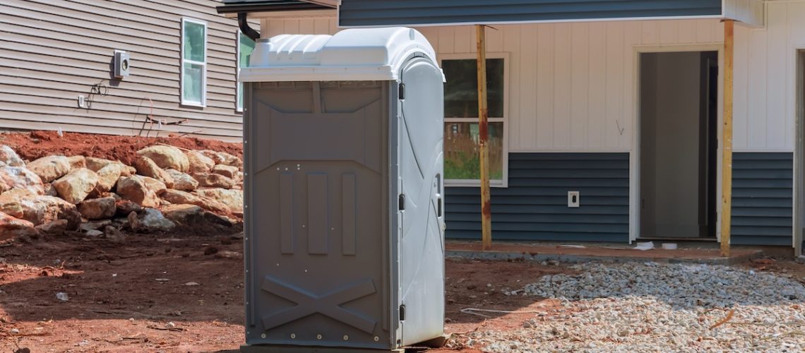 Portable mobile plastic bio toilet cabin stalls are located during construction of house on a construction site