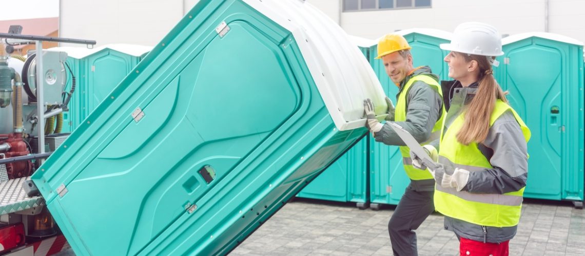 Worker loading portable toilets on truck
